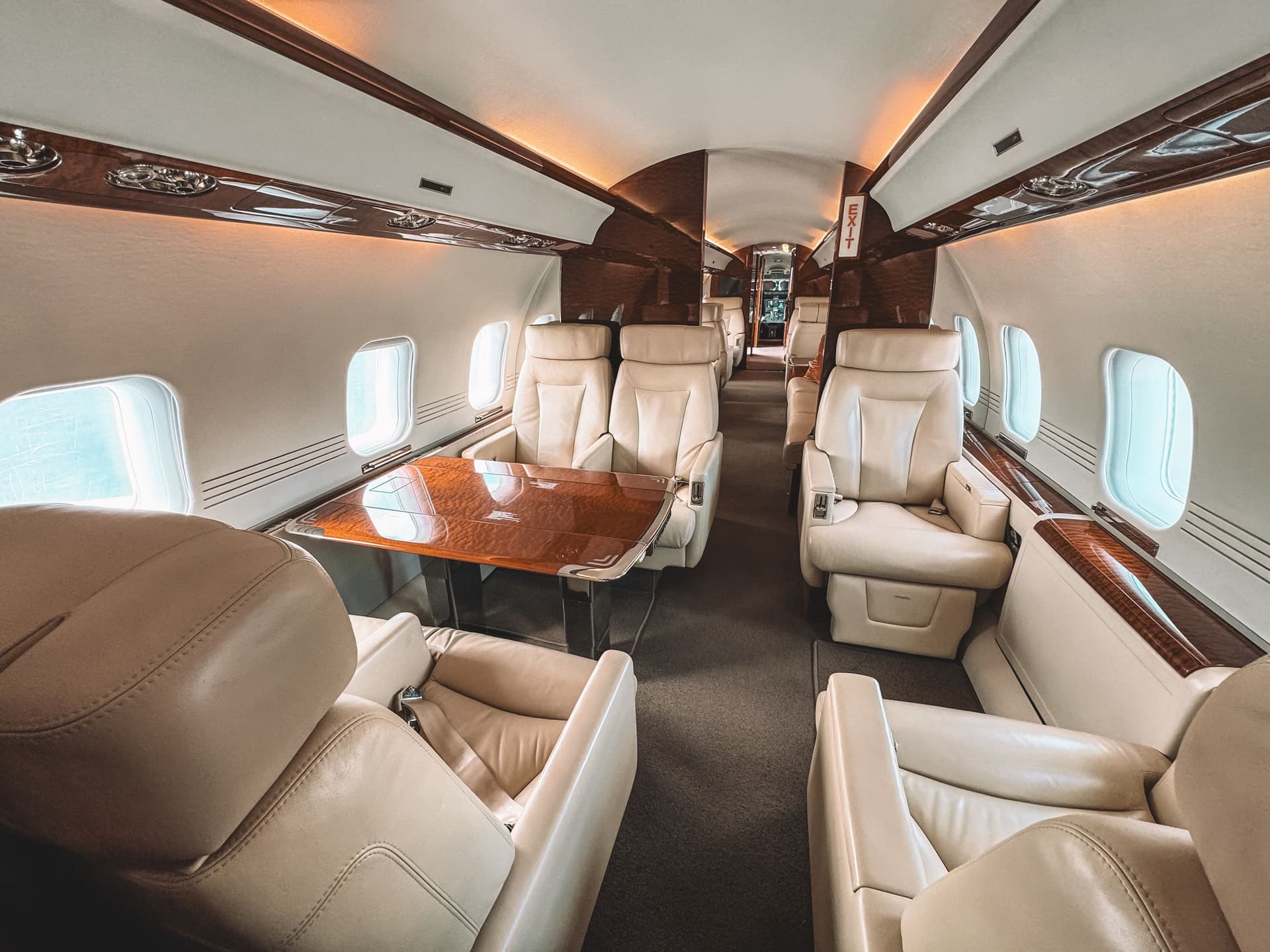 Cream leather seating and wood finishes inside a private aircraft cabin