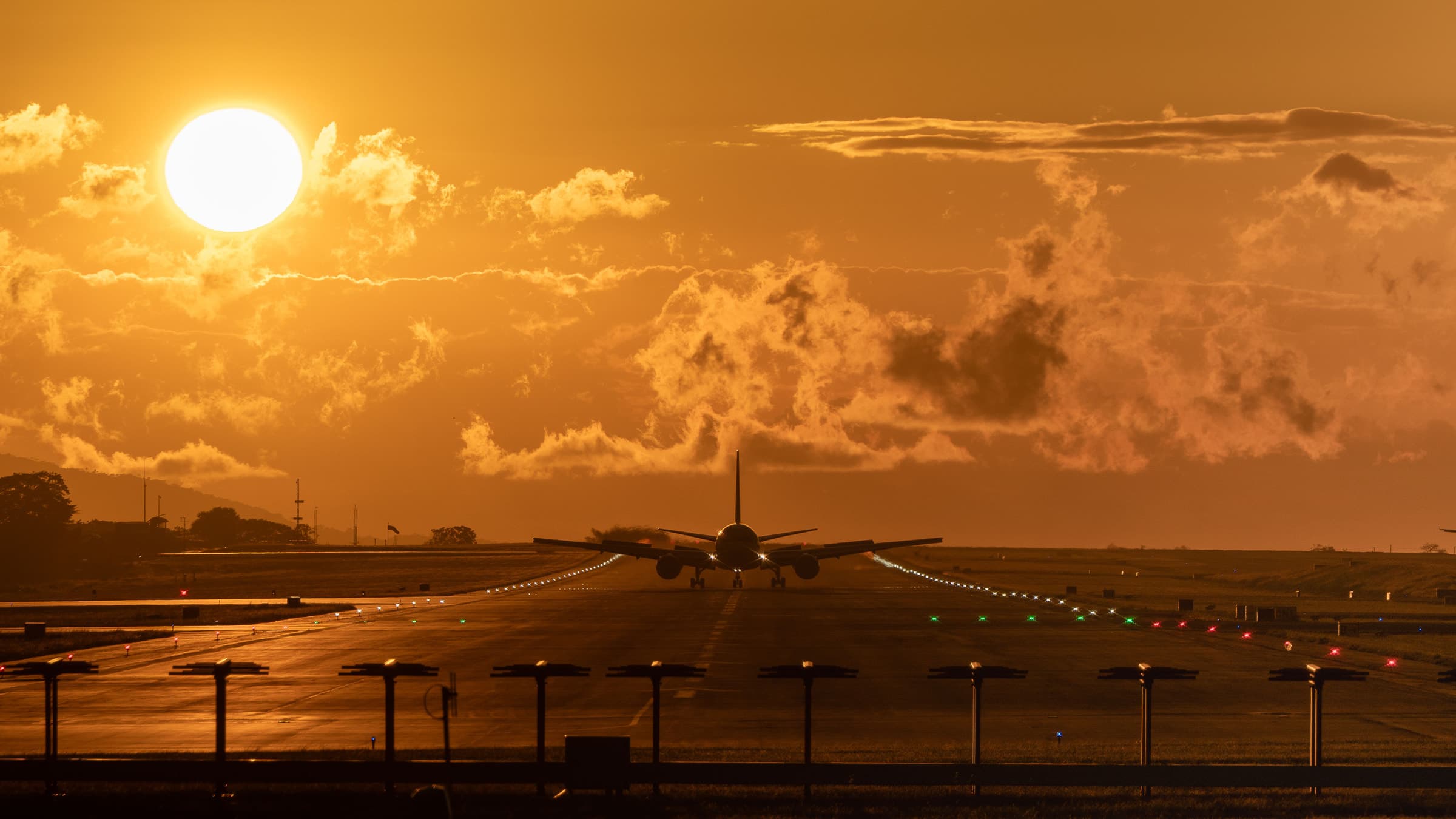 Aircraft on an illuminated runway beneath a golden sunset