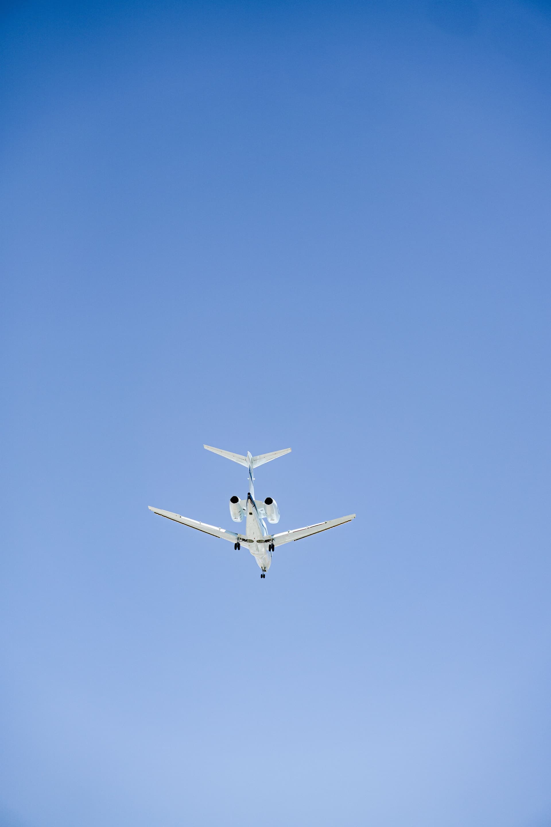Private jet seen from below against a clear blue sky