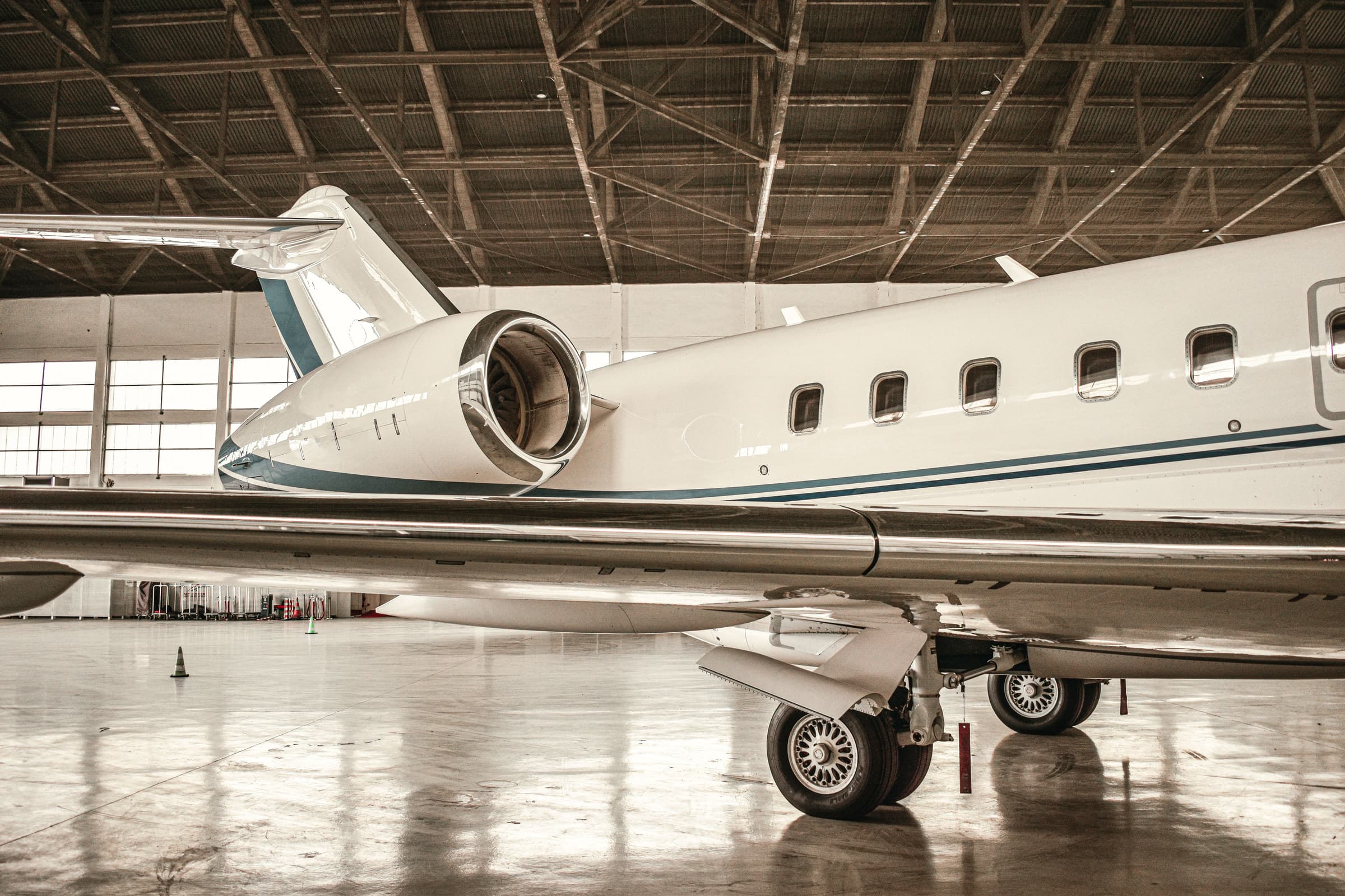 Wing and rear-mounted engine of a private jet inside a hangar